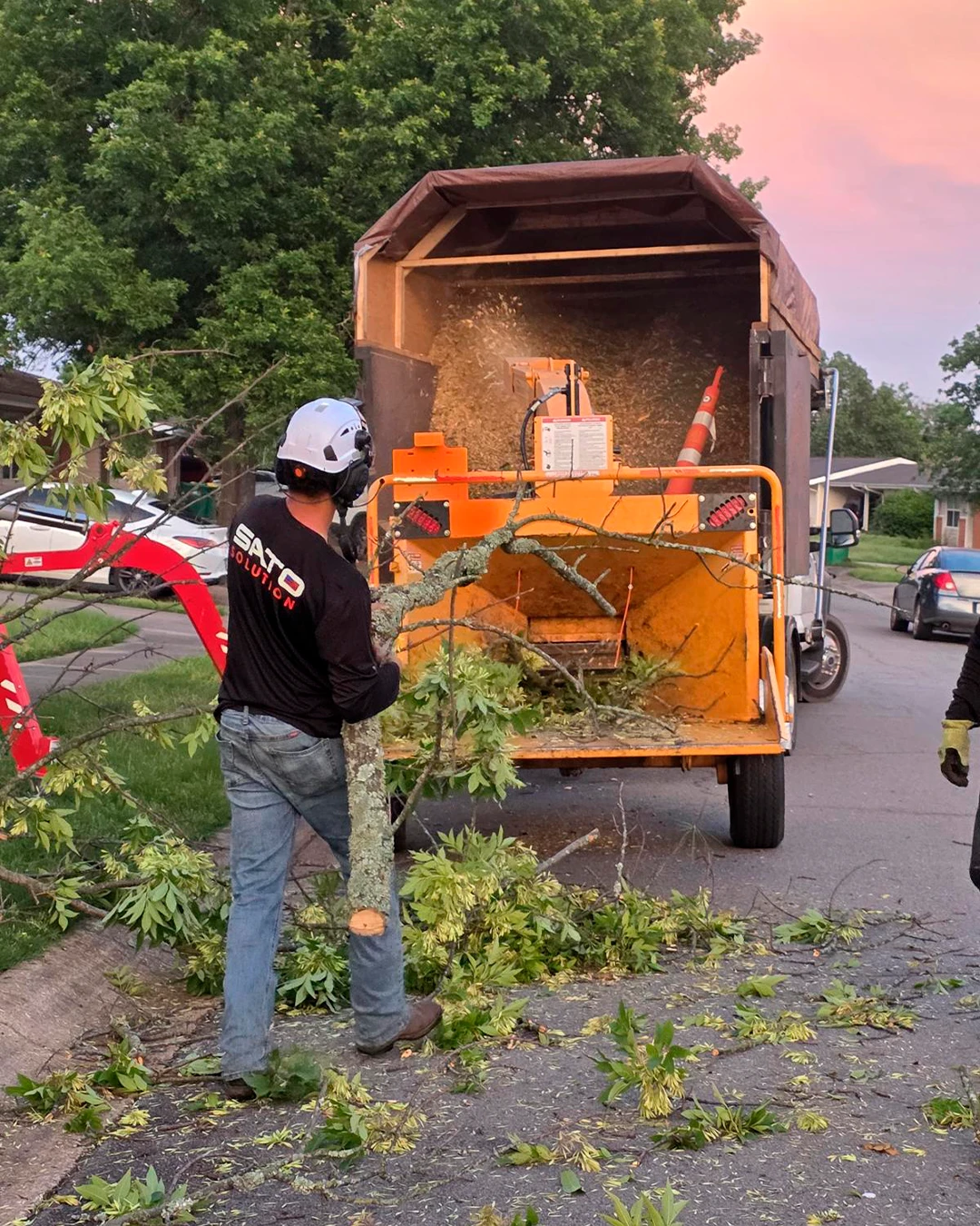 Sato crew feeding branches into a wood chipper